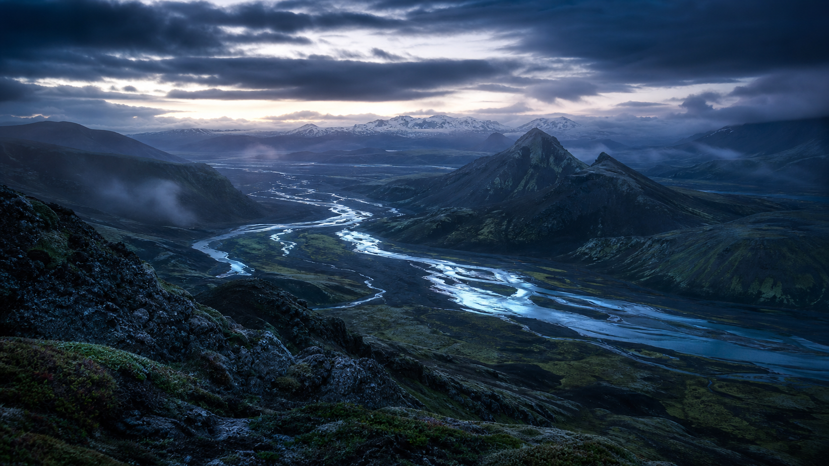 A braided glacial river winding through a misty volcanic valley at dawn